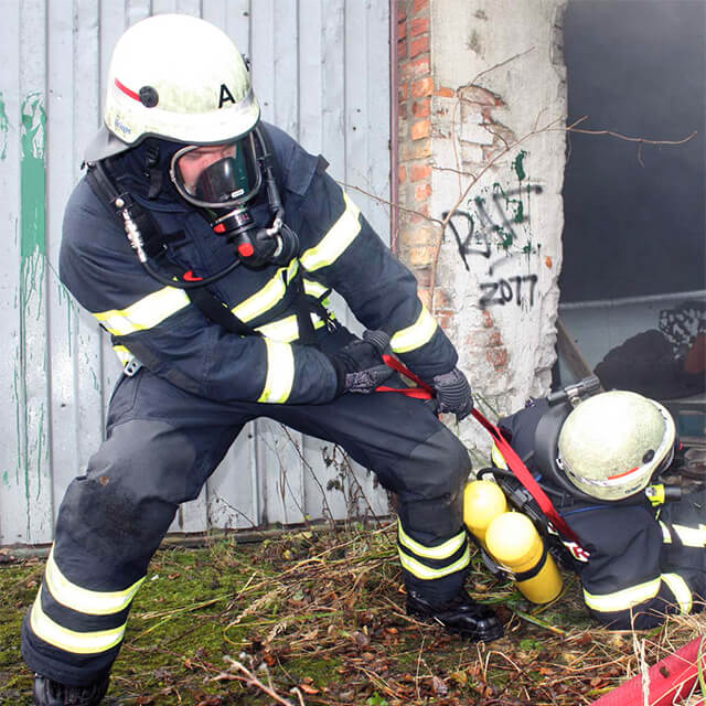 Verunfallter ein Feuerwehrangehöriger wird von einem Kollegen gerettet.